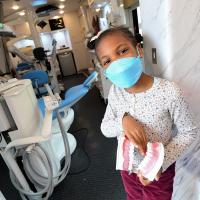 A girl on board the mobile clinic holds a model of a mouth